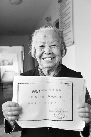 吴惠萍高兴地展示入党55年证书。　　本报记者 古月 摄