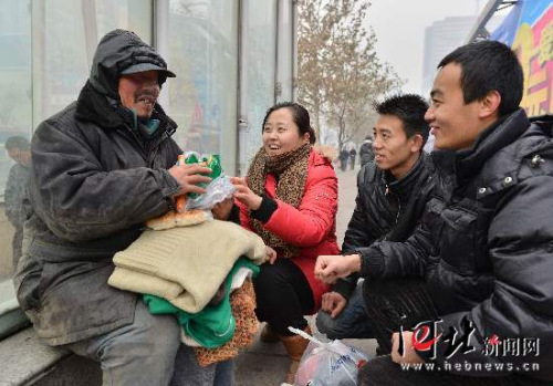  12月12日，石家庄几名公交志愿者正在将棉衣、食品送到一位流浪者手中。入冬以来，公交志愿者开展“暖冬行动”，为20多名街头流浪人员送去了御寒物品。河北日报记者陈腾飞摄