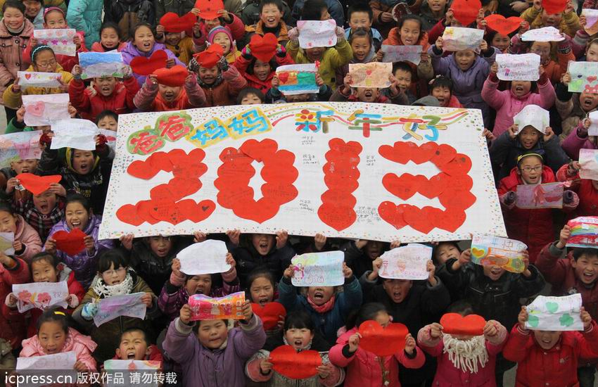 2012年12月28日,河南省温县黄庄镇西林召小学留守儿童在展示“2013爸爸妈妈新年好”字样的巨幅贺卡,并遥祝爸爸妈妈新年好。徐宏星/东方IC