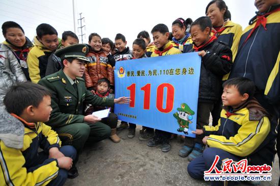 图为边防民警向学生们讲解110报警常识