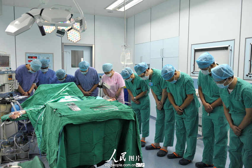 7月17日，专家组在进行等人体器官捐献移植手术前向李杰默哀。(郝亚鑫/人民图片)