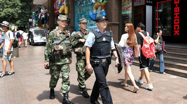  7月30日，上海市公安局黄浦分局特种机动队民警吴晟（前）和武警战士在南京路步行街上巡逻。